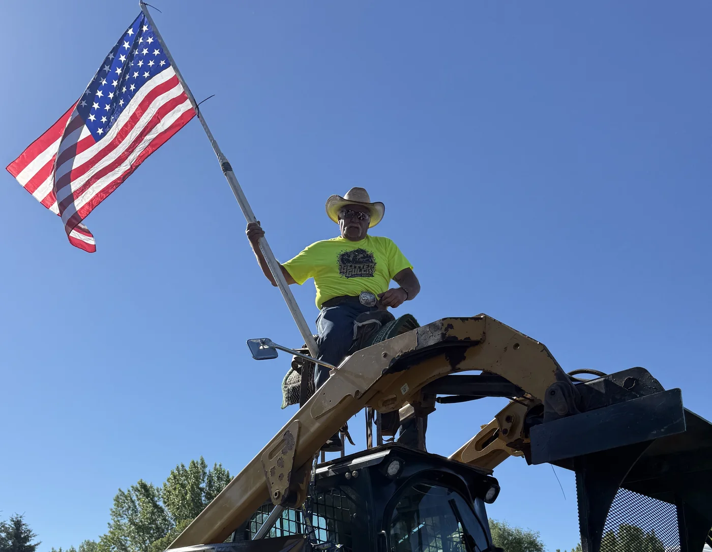 Dave Chambers, owner of Glitter Gulch Ground Works, on his skid steer holding the American flag